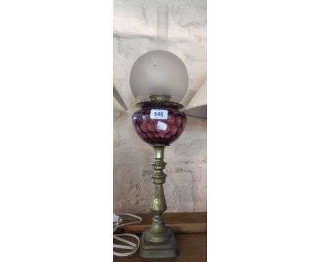 A vintage brass oil lamp with purple glass reservoir, glass shade and chimney