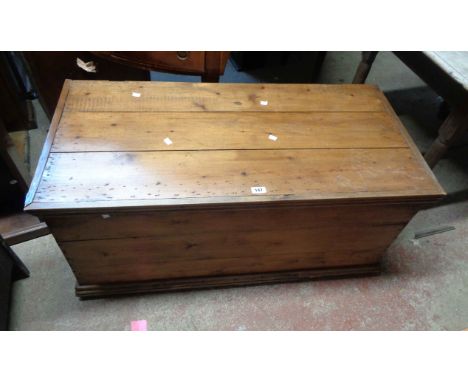 A 1.1m old waxed pine lift-top trunk with flanking iron drop handles, set on moulded base