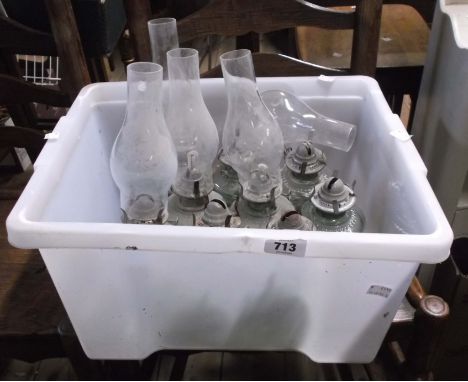 A crate containing a quantity of vintage oil lamps with glass bodies - some with chimneys