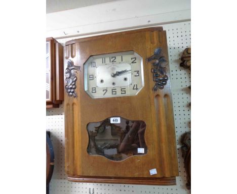 A vintage Jura large polished oak cased wall clock with visible pendulum and eight day chiming movement