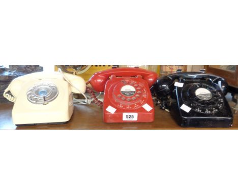 Three vintage dial telephones comprising red and black wall hanging examples and a cream desk top similar
