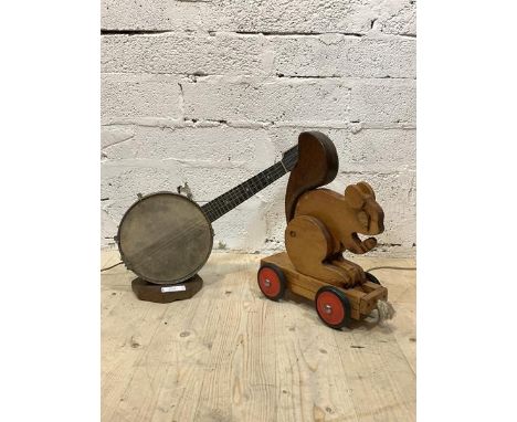 A table light in the form of a banjo, on an octagonal wooden base, (H37cm) together with a child's pull toy formed as a squir