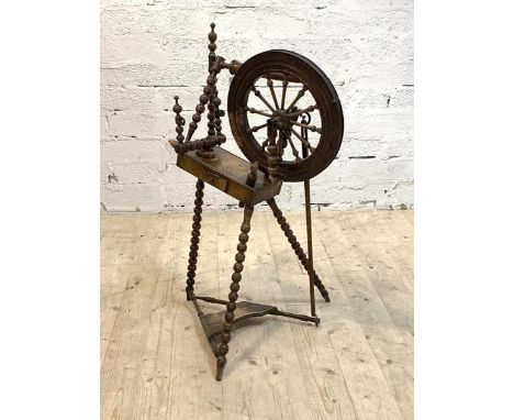 An early 20th century treadle spinning wheel with bobbin turned supports, H92cm