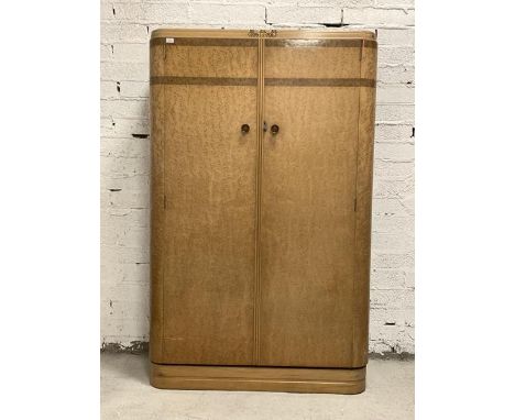 An Art Deco period birds eye maple wardrobe, the caddy top over two doors enclosing an interior fitted with mirror, shelf and