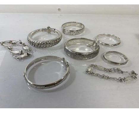 A collection of five inscribed silver bangles (largest: 6cm x 5.5cm) (combined: 88g), a white metal bangle and two bracelets,