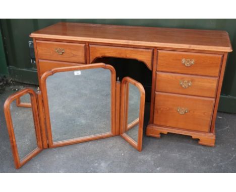 Younger furniture kneehole dressing table on bracket feet (133cm x 56cm x 69cm) and a triple mirror with brass finials, (2) 