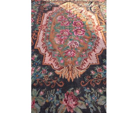 20th C tapestry rug, black ground central medallion with pink roses and rose patterned border (237cm x 330cm) 