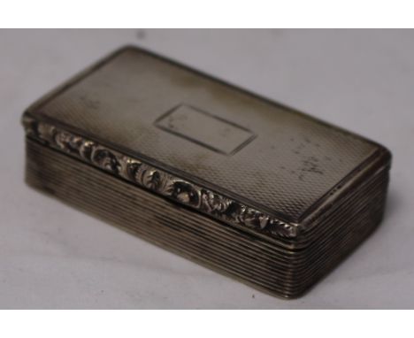 		A silver snuff box. The engine turned lid with vacant cartoosh and foliate cast rim. Reeded body with gilded interior. Birm