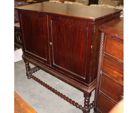 		A mahogany cabinet. The pair of panel doors enclosing two drawers. Raised on barley twist turned supports and stretchers. 4