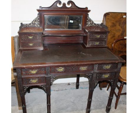 		An Edwardian mahogany writing table. Fret and blind fret carved in the Chinese taste. The soup structure with four drawers 