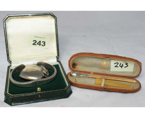 		A silver hinged bangle, a white metal lighter together with a cased amber cigarette holder and a silver cheroutte. C.R. All