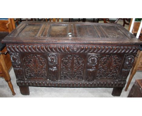		A 17th Century joined oak chest, the four panel fielded lid over three panel front. Heavily carved with representations of 