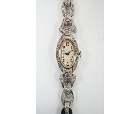 A lady's Zenith white metal and diamond cluster set manual wind oval cocktail watch, on a twin fabric strap, 15cm, gross weig
