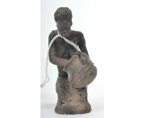 An early 20th Century West African tribal clay sculpture figurine statue of a nude woman. Kneeling down handling her pot and 