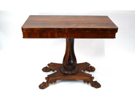 A Regency rosewood fold over card table with unusual shaped tri-form support to a quad platform base, raised on well carved p