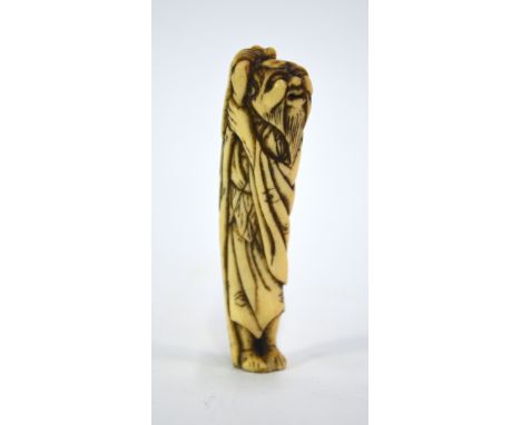 A stag antler netsuke of a standing Sennin, holding a staff and with different sized holes for the himotoshi; 8.5 cm high, Ed