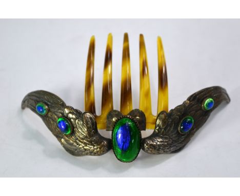 An Edwardian Arts and Crafts hinged hair comb having central blue and green glass cabochon having stylised peacock wings on e