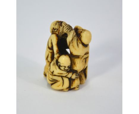 An ivory netsuke carved as three blind masseurs (amma) fighting with each other, 4cm high, unsigned, 19th CenturySome wear or