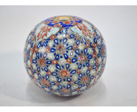 An Ottoman style, hanging ornament of spherical form, decorated with blue, orange and black motifs, 16 cm high

This style of