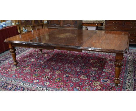 A large Victorian style mahogany dining table, the wind action top extending to accept two insert leaves, raised on semi-bulb