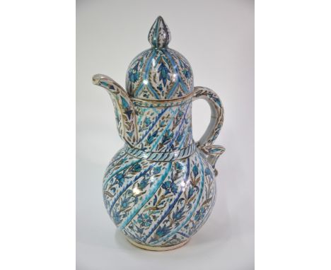 A Kuthaya style pottery ewer and cover with domed cover and knop finial, decorated with floral designs in spiralling panels, 