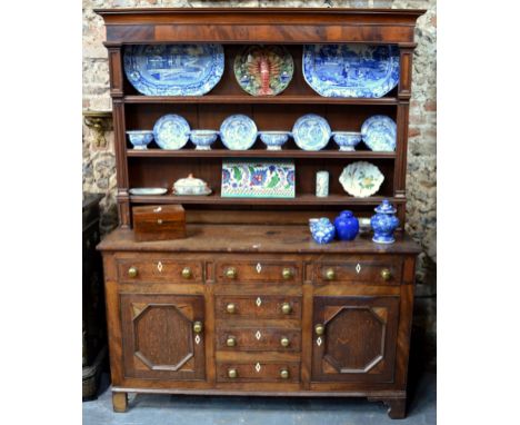 A George III mahogany and oak high dresser, the three tier plank backed rack over an arrangement of six drawers and two cupbo