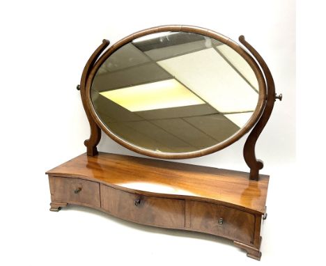 An early 20th century figured mahogany toilet mirror, the oval swing mirror above a serpentine front fitted with three drawer