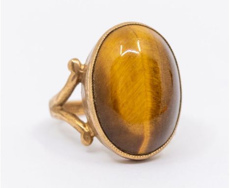 A tigers eye quartz and 9ct gold dress ring, comprising an oval quartz approx 12 x 17mm, to spit scrolled shoulders, size K, 