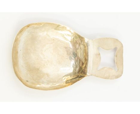 An Arts &amp; Crafts style large white metal caddy spoon, planished bowl with pierced quatrefoil decorative panel to handle, 
