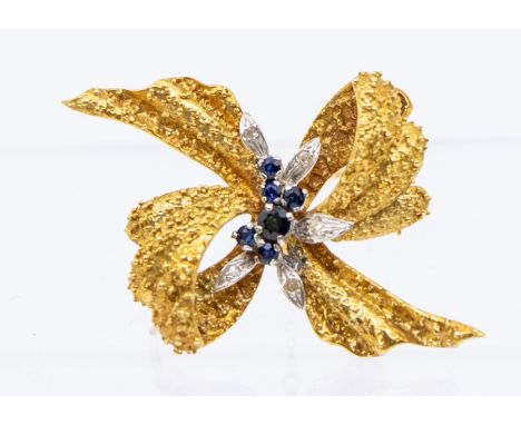 A vintage sapphire and diamond 18ct gold brooch, comprising a textured bow form with centrally set round cut sapphires of var