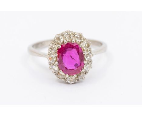 A ruby and diamond platinum cluster ring, comprising an oval cut ruby approx 1.10 carats, within a border of brilliant cut di