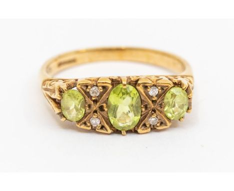 A vintage peridot and diamond 9ct gold ring, comprising three oval peridot stones with double diamond set accents, scrolled s