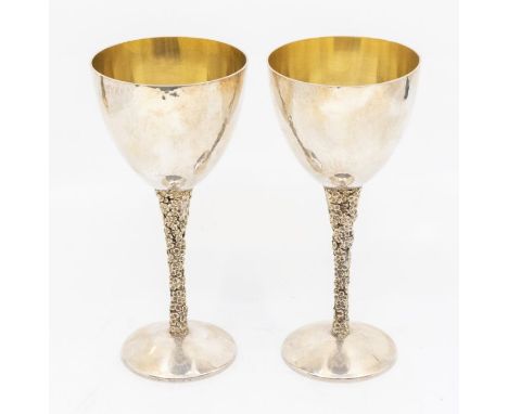 Stuart Devlin: a pair of Modernist silver goblets, planished bowls above textured floral tapering stems, on plain planished b