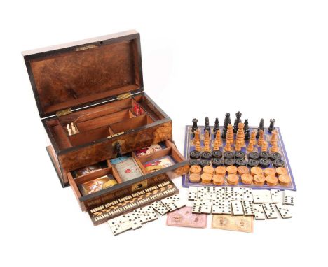 A Victorian Circassian walnut and ebonized rectangular games box containing a compendium of games. To include turned and carv
