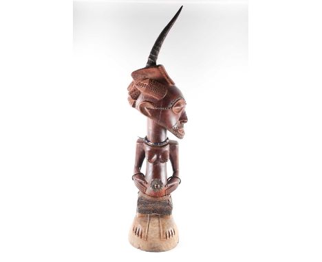 A Songye maternity standing power figure, Nikisi, Democratic Republic of Congo, with central animal horn charge above a linea