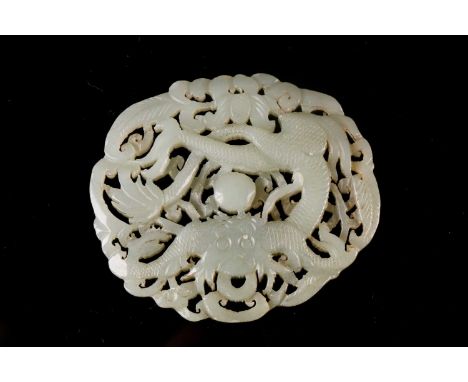 A Chinese celadon jade plaque, carved with a dragon surrounding a pearl, amongst leafy tendrils, 7cm dia