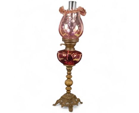 Antique cast and pierced brass oil lamp, with cranberry glass font and shade, with chimney, H67cm 
