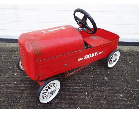 Triang - A vintage Triang 'Duke' pressed steel pedal car. The car in red with white spoke metal wheels, rubber tyres, black s