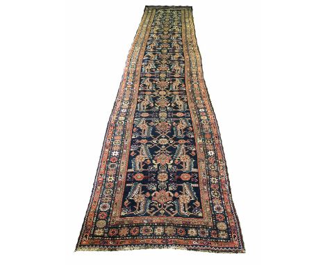 ANTIQUE NORTH WEST PERSIAN RUNNER, 485cm x 96cm, palmette and kalax leaf on an all over midnight blue field within matching b