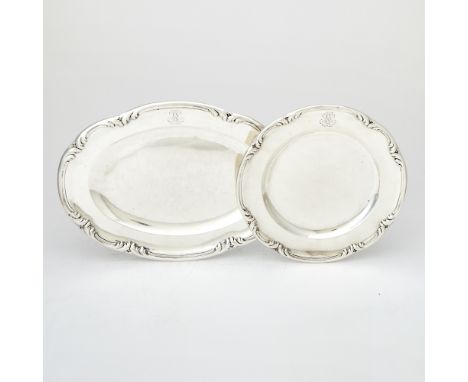 Each with a foliate scroll border, comprising an oval example, length 15 inches (38 cm), and a circular example, diameter 11 