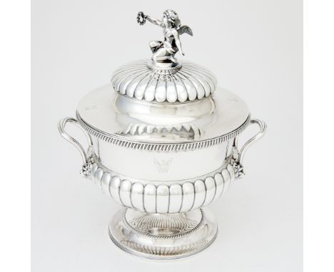 The circular part lobed body with reeded handles with lion mask joins, the part fluted domed cover with a putti finial. Heigh