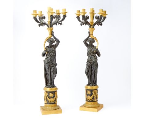 Each in the shape of a patinated bronze caryatid supporting six candle branches, raised on a circular socle with square-shape