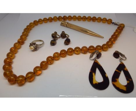 A row of Baltic amber beads, tortoiseshell earrings, rolled gold propelling pencil and a silver dress ring 