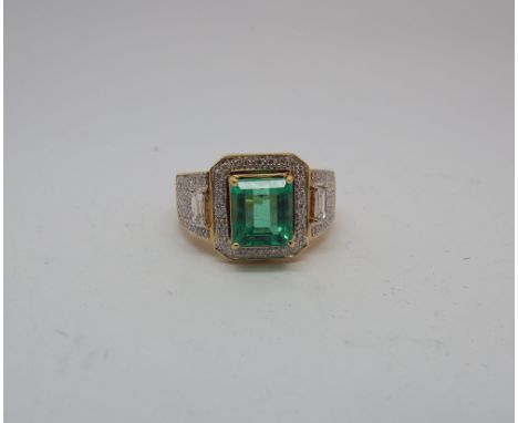 Large and impressive emerald and diamond cluster ring on an 18ct yellow gold shank set with rectangular emerald surrounded by