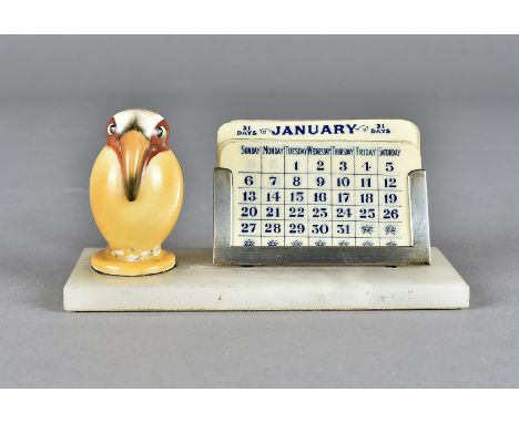 An art deco desk calendar, modelled as a ceramic exotic bird on onyx base with changeable ivorine month panels, 11 cm wide x 