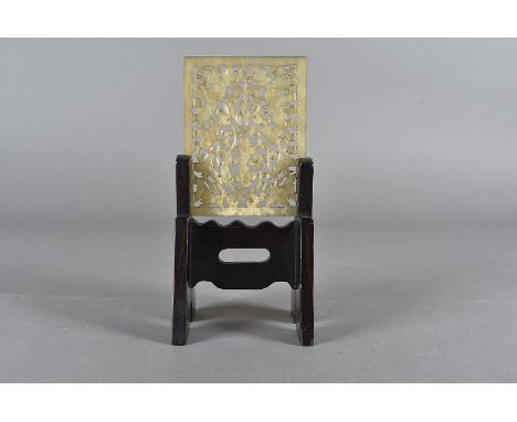 A Chinese jade pierced plaque, decorated with floral design, 10.5 cm x 8 cm on a hardwood stand, max 19 cm high 