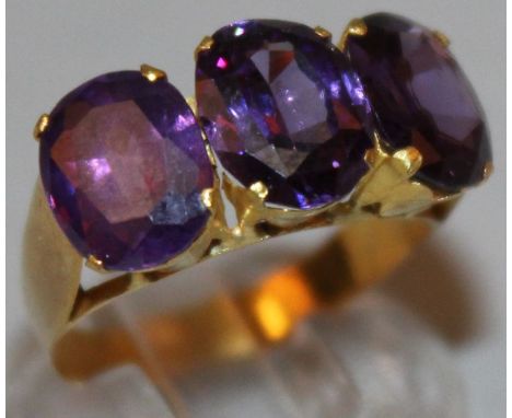 A THREE STONE AMETHYST AND GOLD SET RING. 