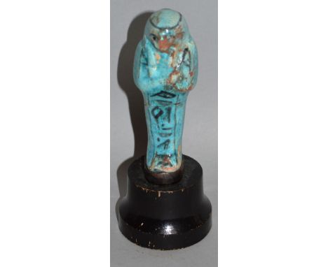 A LIGHT BLUE SHABTI FIGURE ON A WOODEN PLINTH. 4ins high excluding plinth. 
