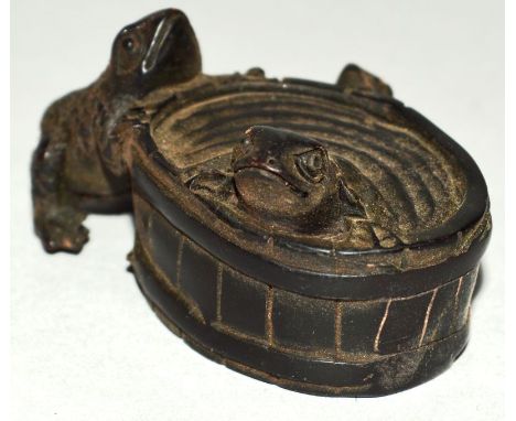 A CARVED WOOD NETSUKE, two frogs on a barrel. 