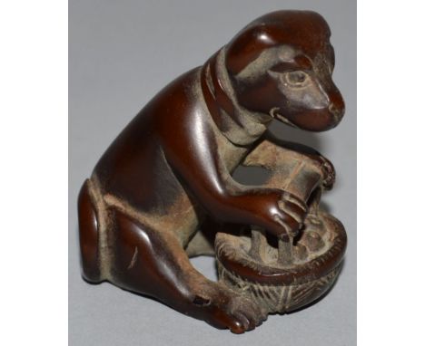 A CARVED WOOD NETSUKE, a bear with a basket of fruit. 